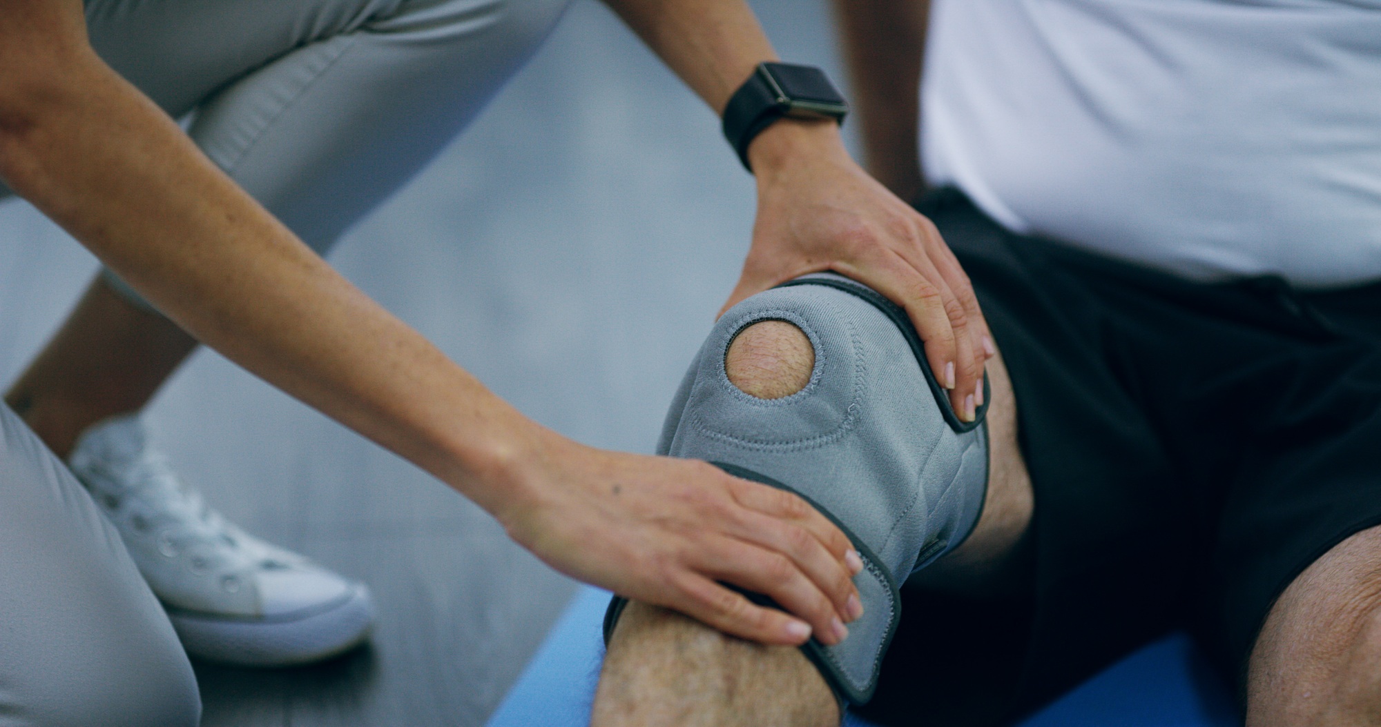 Knee pain, physiotherapy and hands of patient with brace for support, medical service and consultin